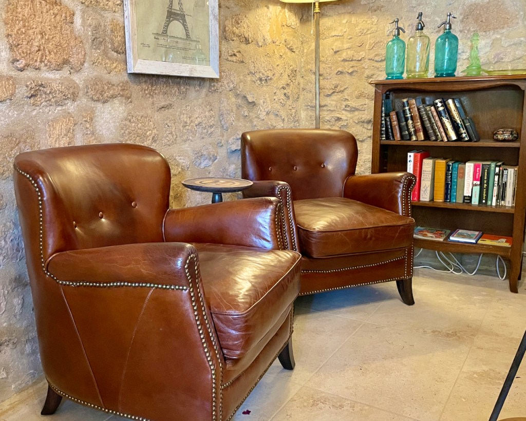 Maison Delluc- Two leather club chairs offer a comfortable and cozy sitting space in our reading nook at the foot of the stairs